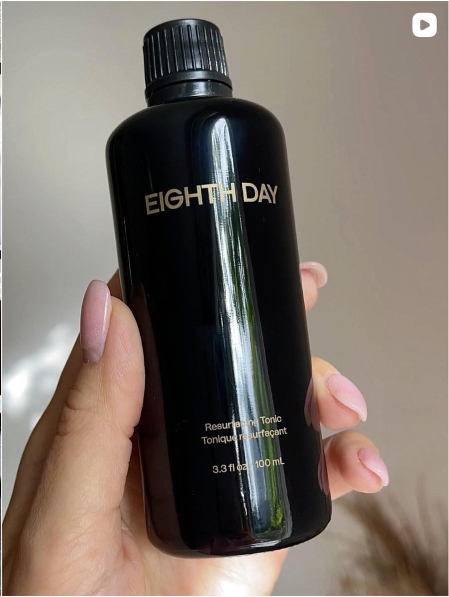 Hand holding a black Eighth Day Resurfacing Tonic bottle with gold lettering