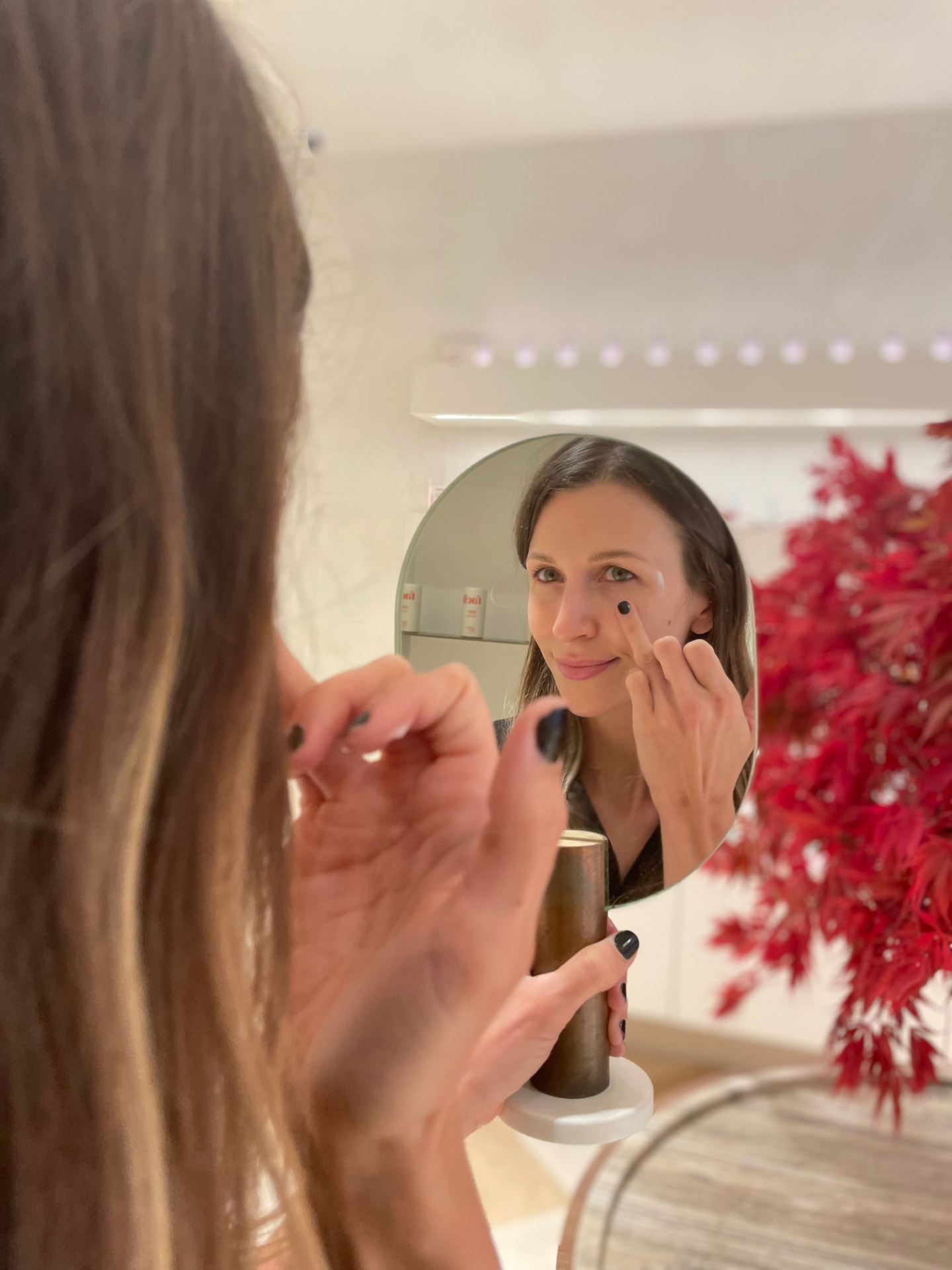 Close-up of a woman applying Facile product in front of a mirror