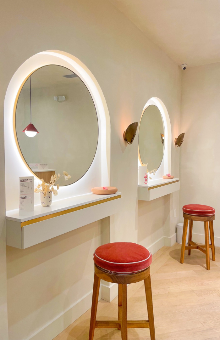 Arched vanity mirror stations with brass sconces inside the flagship