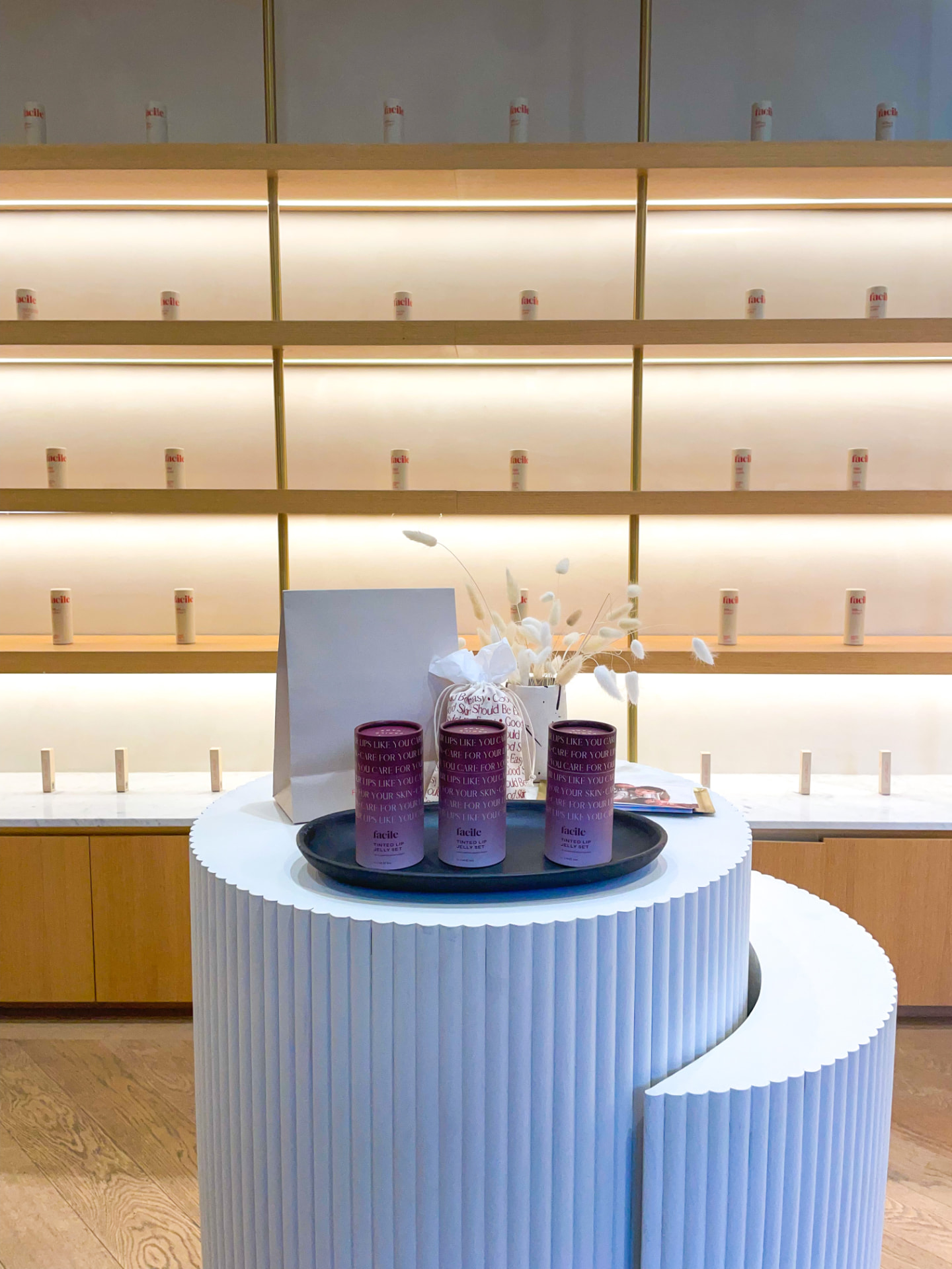 Scalloped display pedestal with Facile Tinted Lip Jelly cylinders and tubes inside the flagship