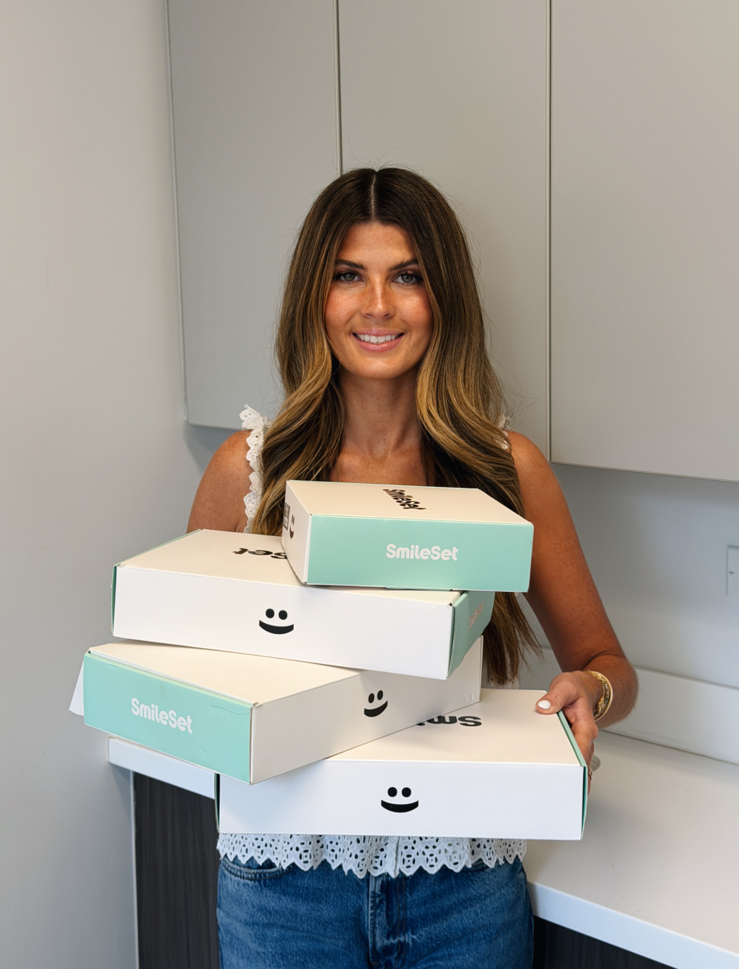 Woman holding a stack of SmileSet branded boxes