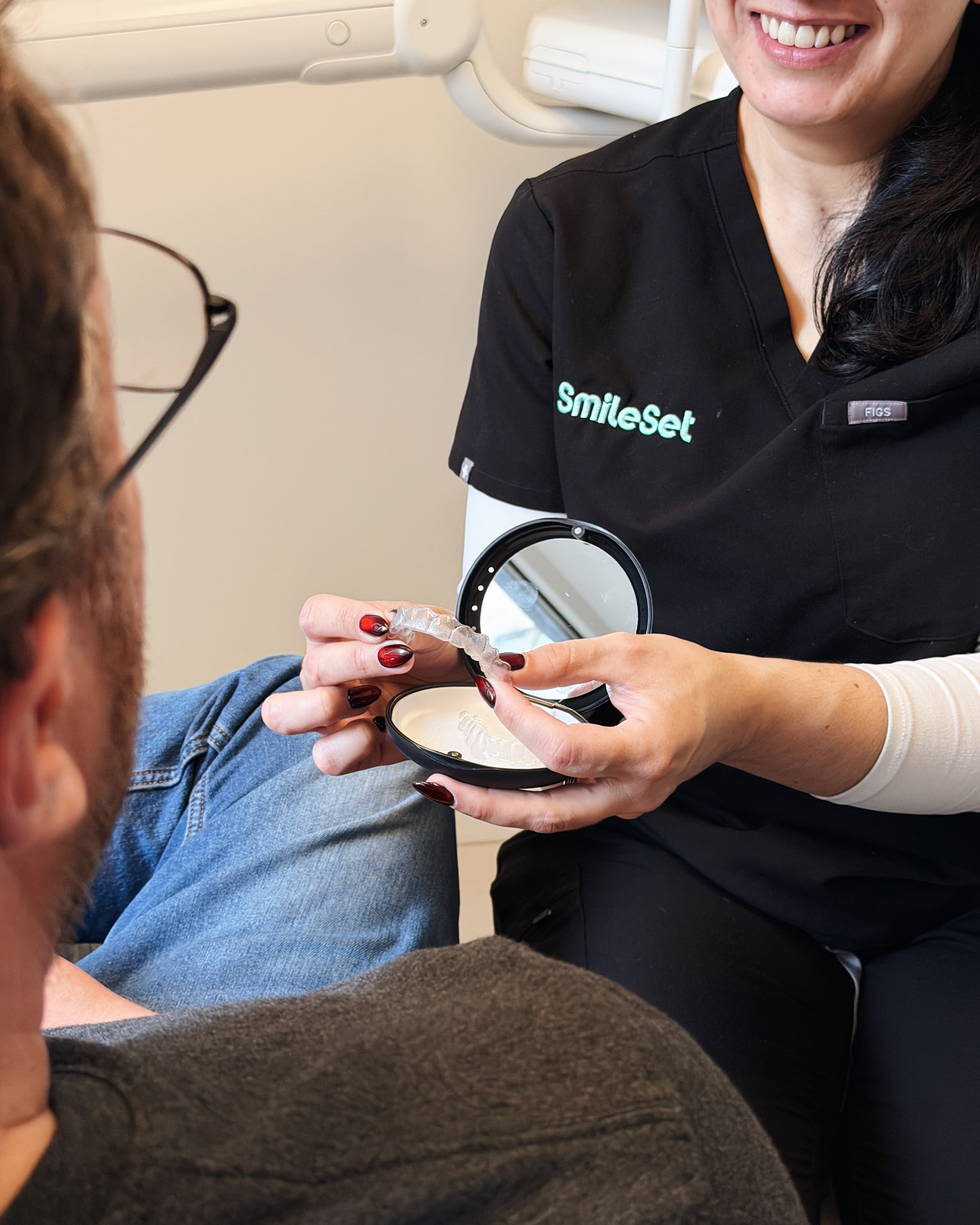 SmileSet team member showing a patient their aligners in a mirror