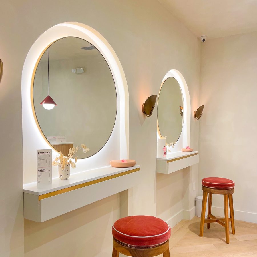 Arched vanity mirrors and red stools inside the Facile flagship