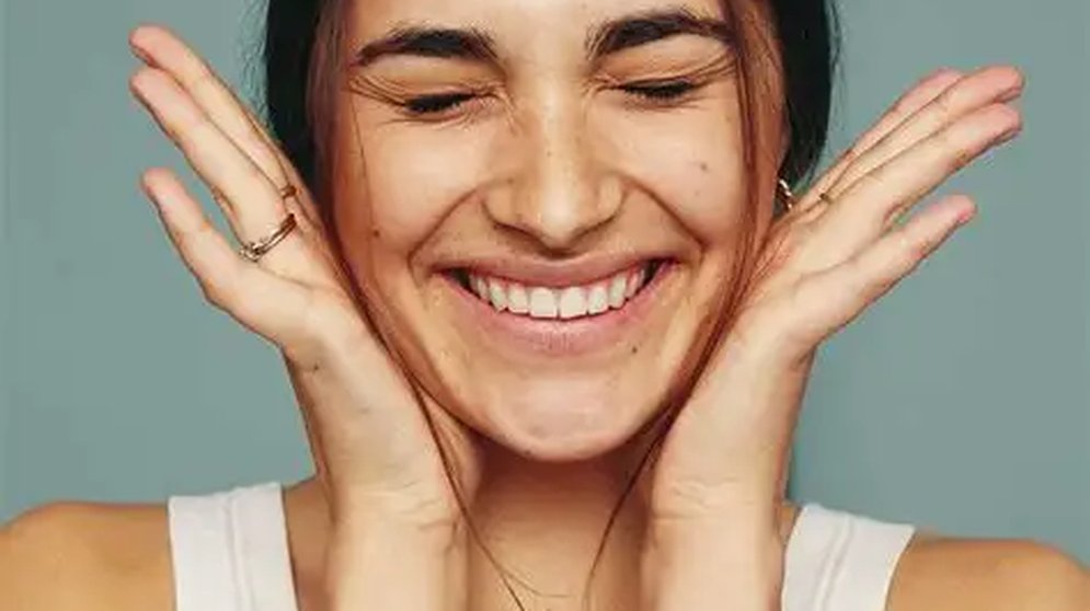 Woman smiling with her eyes closed, hands framing her face, SmileSet