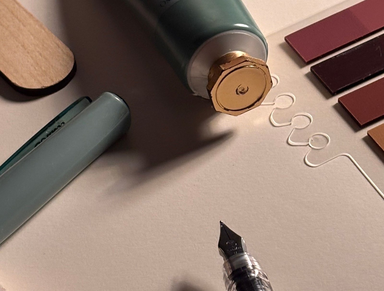Fountain pen, hand cream tube, and color swatches on cream paper